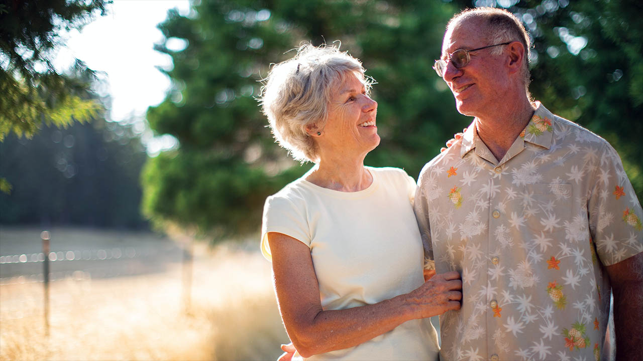 old, female and male couple linking arms while smiling